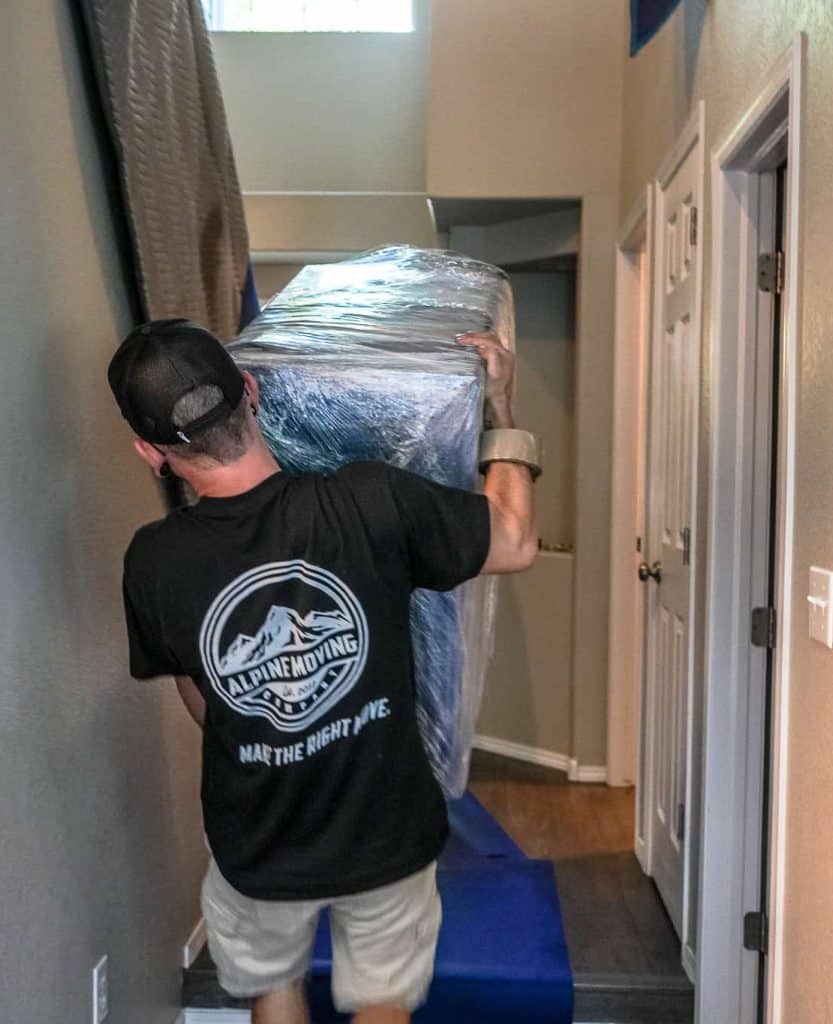 Mover carrying large wrapped item in hallway