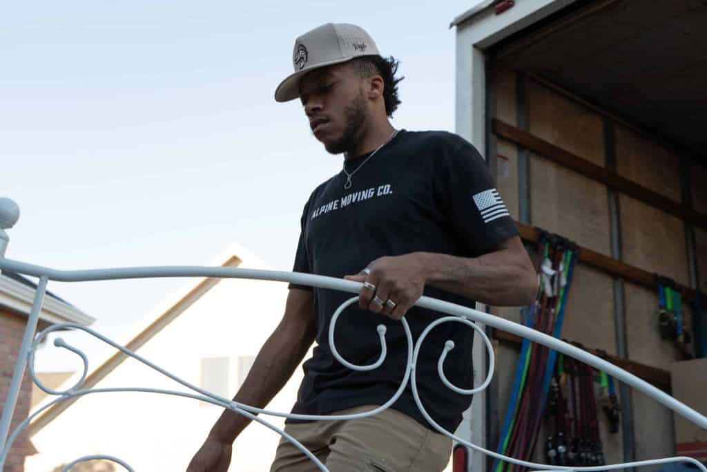 Mover carrying metal headboard into truck