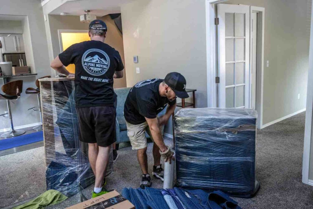 Movers wrapping furniture for relocation.
