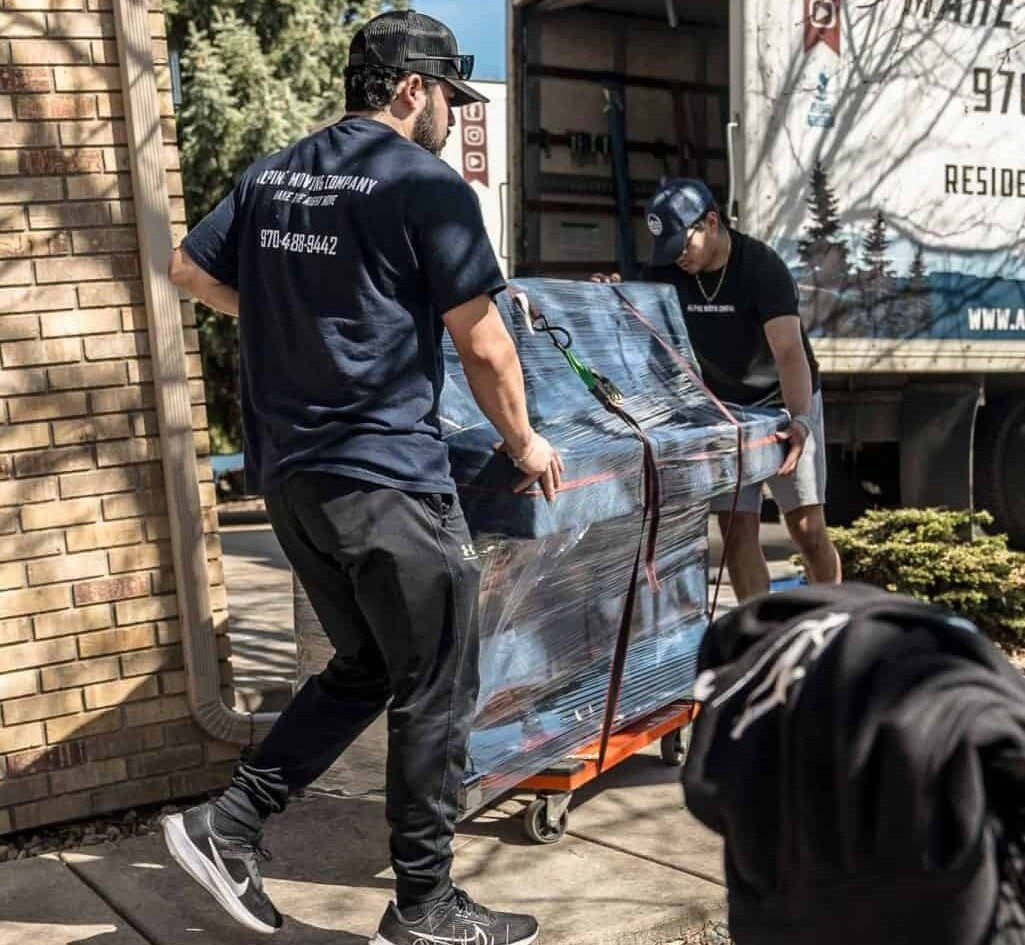 Movers transporting wrapped furniture to truck