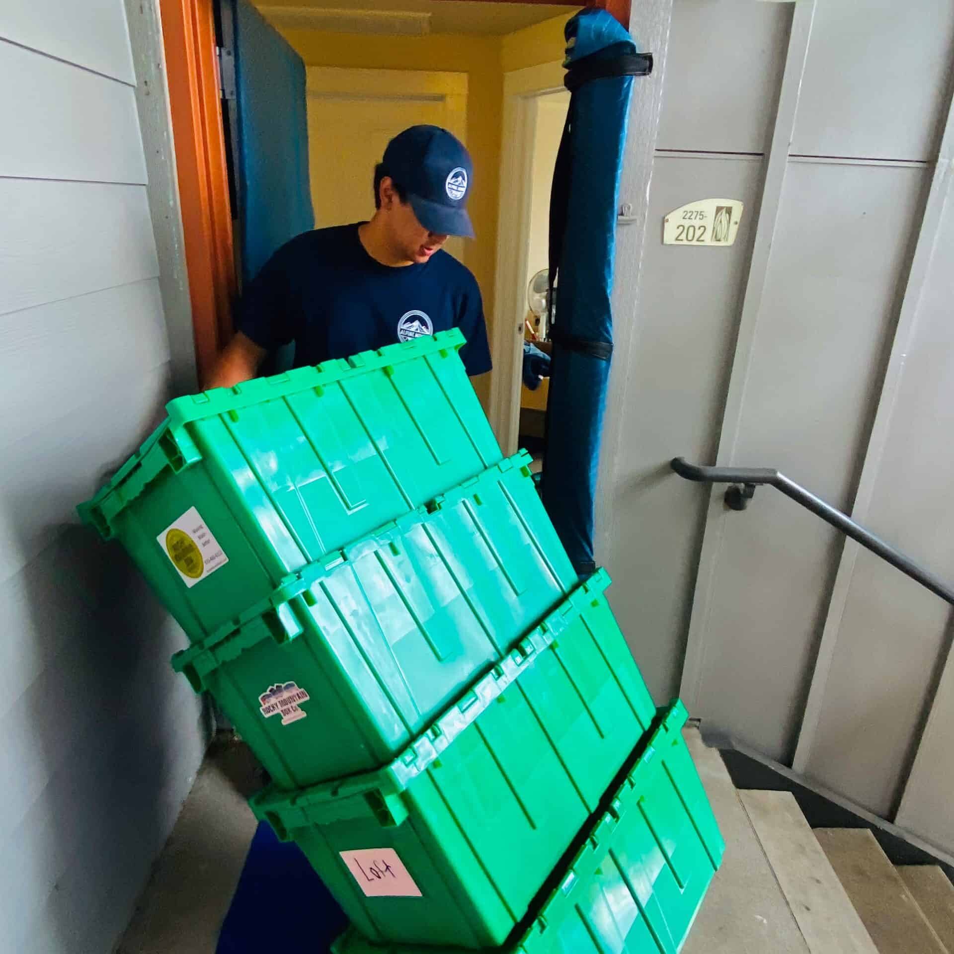 Person moving stack of green crates through door