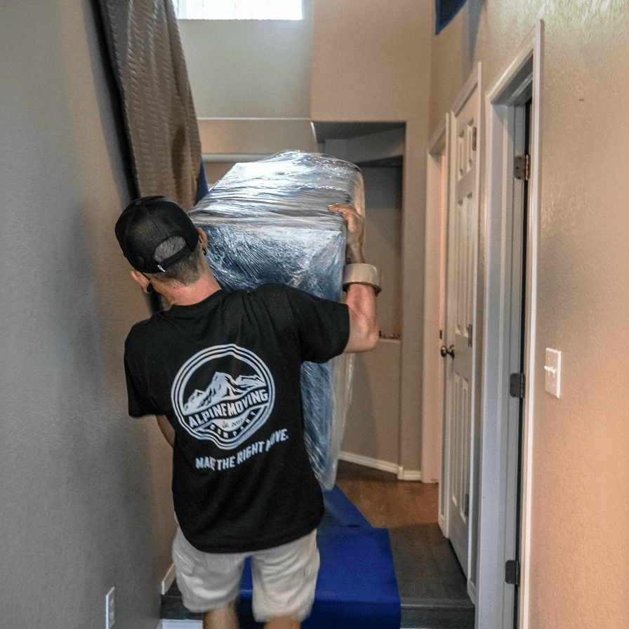 Denver moving company carrying furniture through narrow hallway.