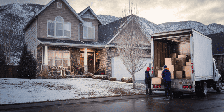 Snowy Colorado home with a moving truck and crew unloading boxes, showing moving during the holidays.