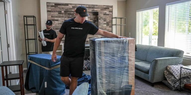 Movers wrapping furniture in living room.