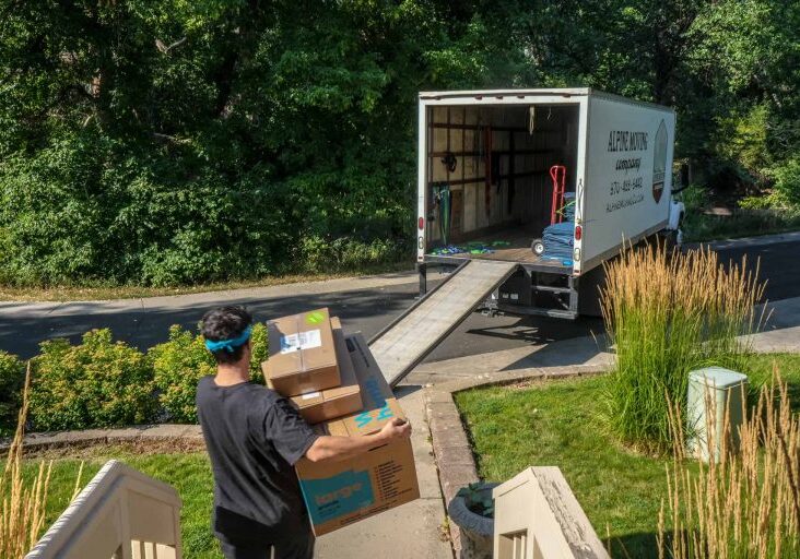 Person moving boxes into truck on driveway.