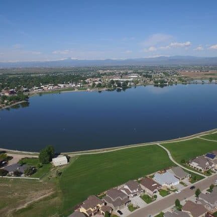 Aerial view of lake surrounded by homes and greenery.